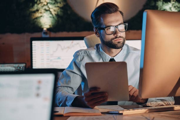 Confident young man working on computer while staying late in the office A tecnologia pode direcionar uma empresa no empreendedorismo atual