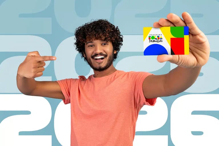 Homem sorridente segurando e apontando para o cartão do programa Bolsa Família em frente a um fundo com o ano 2026.