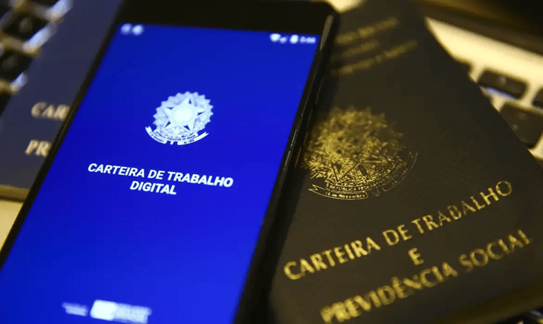Carteira de Trabalho Digital em um celular, com a versão física ao lado, representando o acesso ao seguro-desemprego.