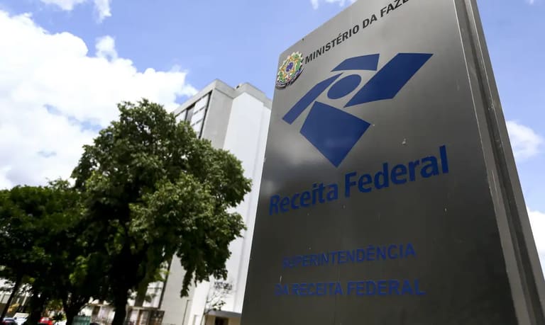 Placa da Receita Federal com o nome e logo visíveis em frente a um edifício público, em Brasília