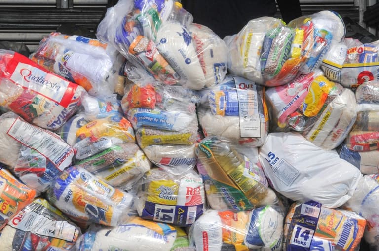 Cestas básicas empilhadas com diversos alimentos.