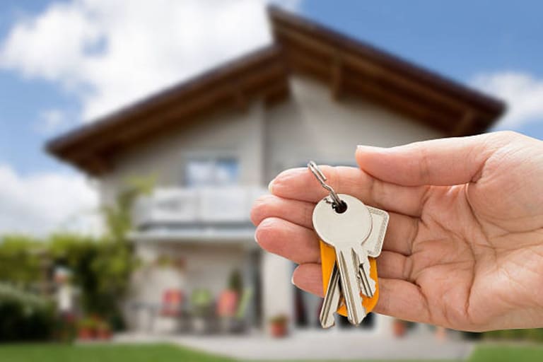 Mãos segurando chave e miniatura de casa simbolizando inscrição online para programa habitacional