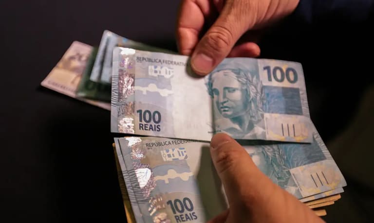 Notas de cem reais representando aumento no salário mínimo regional