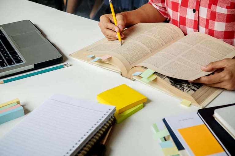 Organização de estudos para concurso público com materiais didáticos Pessoa estudando para concurso público com livros abertos, notebook e materiais organizados na mesa