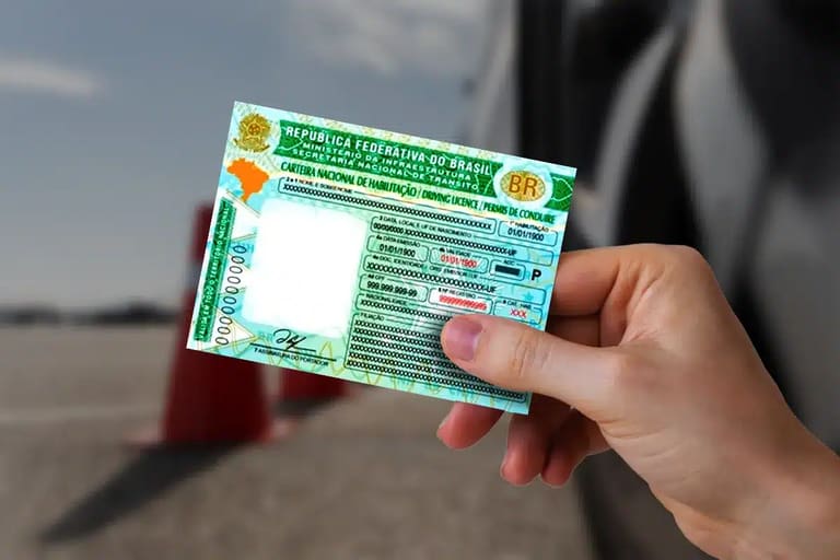 Carteira Nacional de Habilitação Brasileira atual Mão segurando uma Carteira Nacional de Habilitação (CNH) do Brasil com fundo desfocado de pista de direção