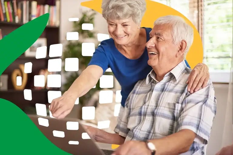 Casal de idosos sorrindo enquanto navegam na internet, simbolizando a importância do acesso à informação para a terceira idade.