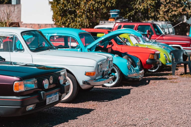 Carros clássicos coloridos estacionados em uma rua.
