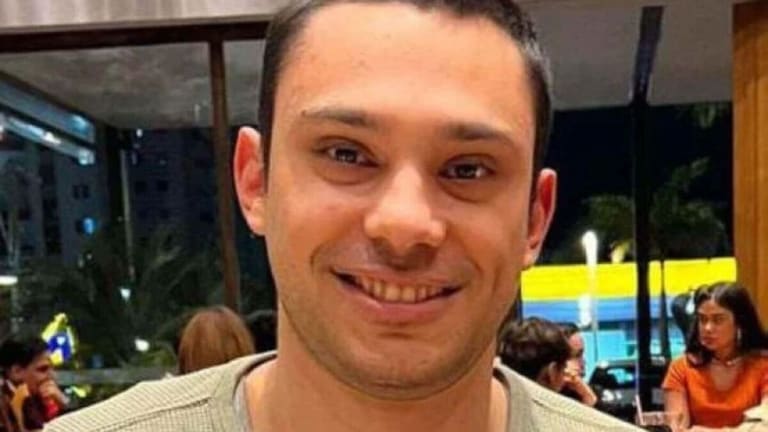 Lucas Vilela Homem adulto sorrindo, vestindo blusa verde clara, em restaurante com pessoas ao fundo