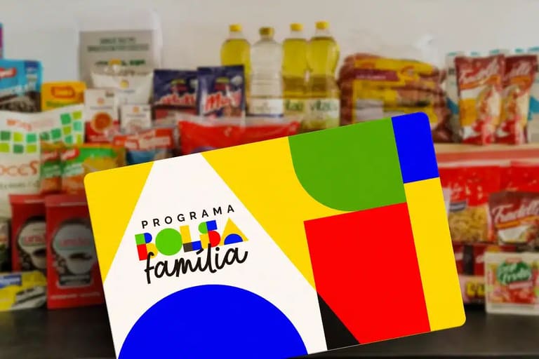 Cartão do Programa Bolsa Família 2026 em frente a alimentos básicos, como óleos, massas e arroz, simbolizando o apoio a famílias de baixa renda.