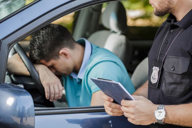 Um policial de trânsito com um clipboard abordando um motorista que parece aflito ao volante, representando as infrações de trânsito e suas penalidades segundo o CTB.