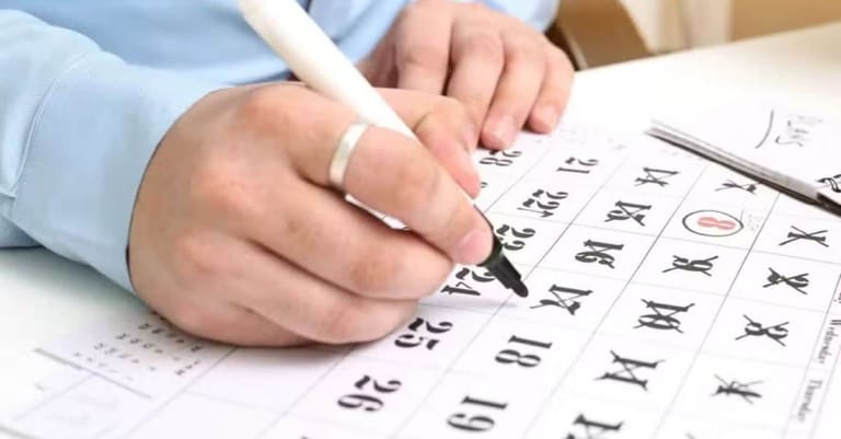 Pessoa escrevendo no calendário, marcando datas importantes relacionadas aos feriados e pontos facultativos de 2026.