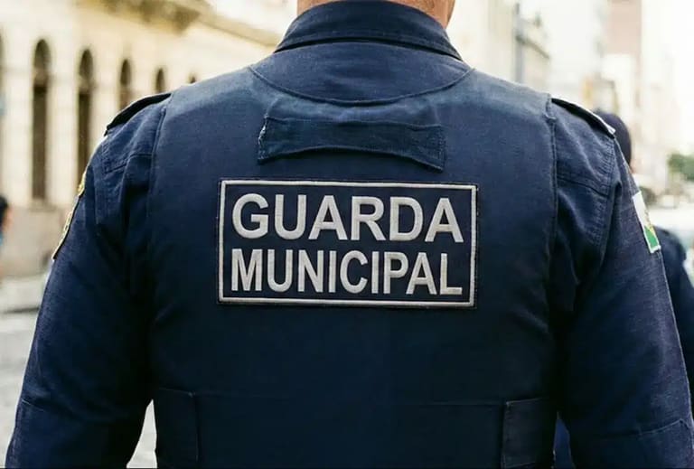 Uniforme de um Guarda Municipal com o texto 'GUARDA MUNICIPAL' visível na parte de trás da camisa, enquanto ele patrulha a cidade, representado a seleção da Prefeitura para o cargo de Guarda Municipal.