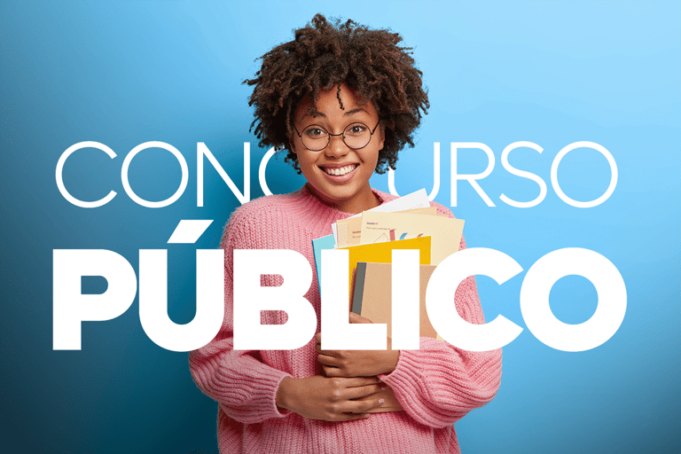 Jovem usando óculos e suéter rosa segura apostilas coloridas sorrindo em fundo azul