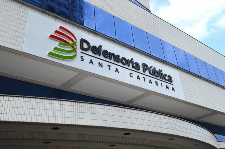 Logotipo da Defensoria Pública de Santa Catarina com anúncio de novo concurso com salários de R$ 24 mil.