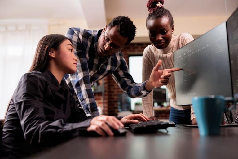 Estudantes de Ciência da Computação em laboratório de informática, com professor orientando análise de código e desenvolvimento de software.