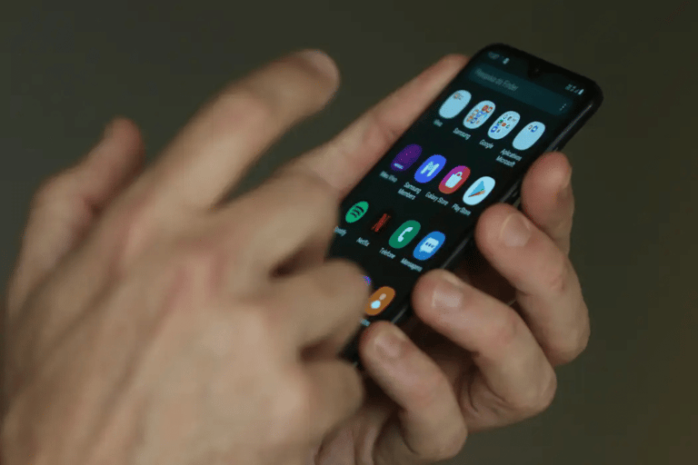 Mãos utilizando smartphone com aplicativos abertos na tela iluminada