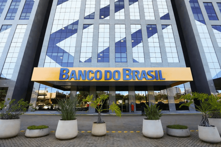 Prédio espelhado do Banco do Brasil com letreiro amarelo e plantas na entrada