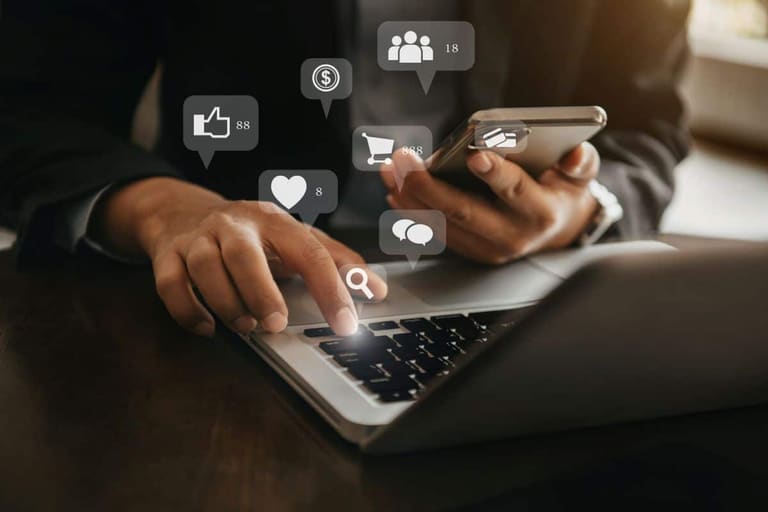 Pessoa utilizando notebook e smartphone enquanto acessa plataformas digitais relacionadas a marketing e vendas online.