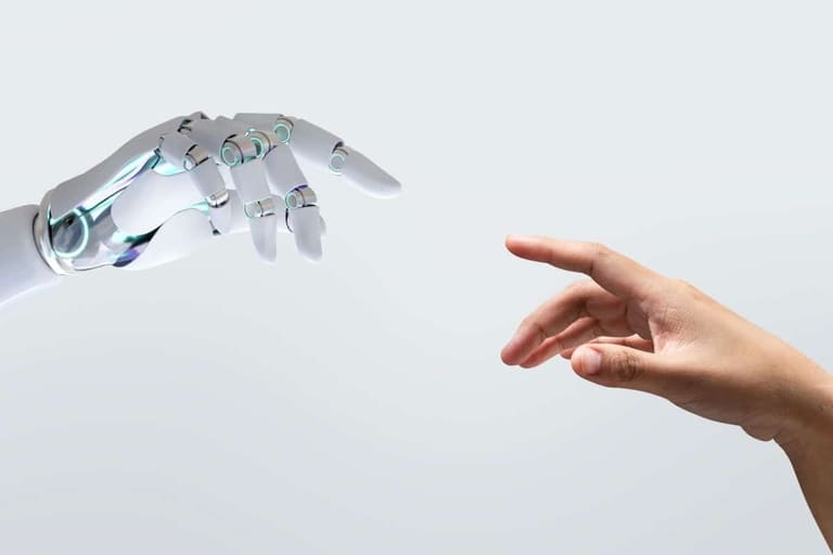 Close em plano médio de uma mão robótica branca e articulada e uma mão humana de pele morena se aproximando, quase se tocando, em um fundo cinza claro neutro. A imagem simboliza a interação entre humanos e inteligência artificial no mercado de trabalho.