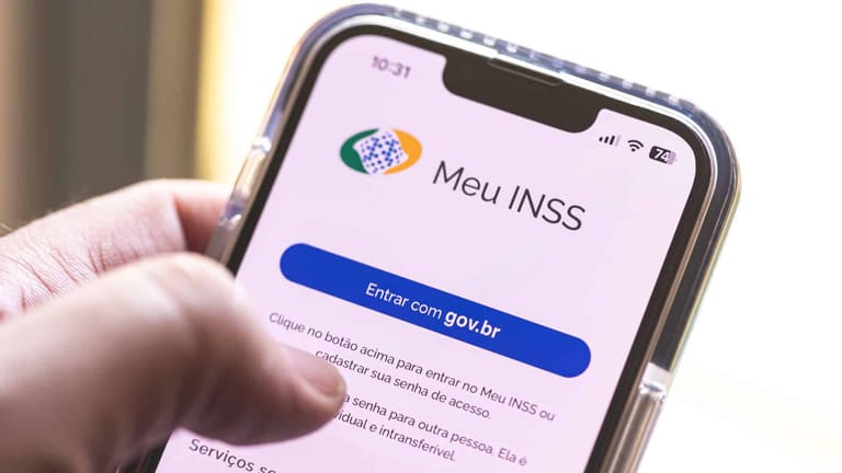 Mão segura celular exibindo tela do aplicativo Meu INSS com botão Entrar com gov.br em destaque