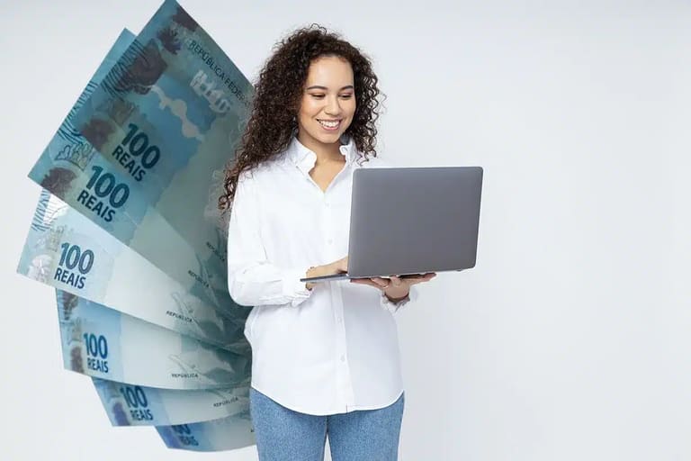 Profissional usando notebook com notas de cem reais ao fundo, representando valorização salarial com qualificação.