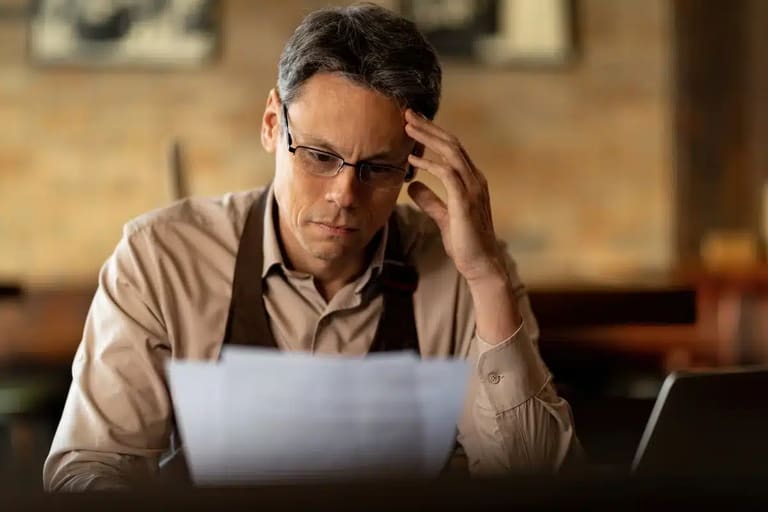 Homem preocupado revisando contas com possibilidade de pagar dívidas usando o FGTS