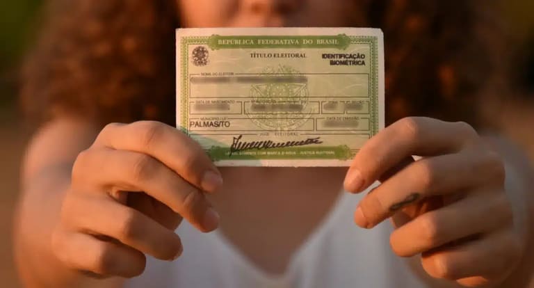 Eleitora segura título eleitoral em destaque durante período de regularização junto à Justiça Eleitoral.