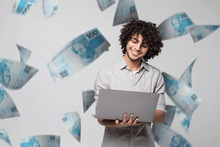 Jovem sorrindo enquanto usa notebook com notas de dinheiro ao redor, simbolizando carreiras bem pagas com menor nível de estresse.
