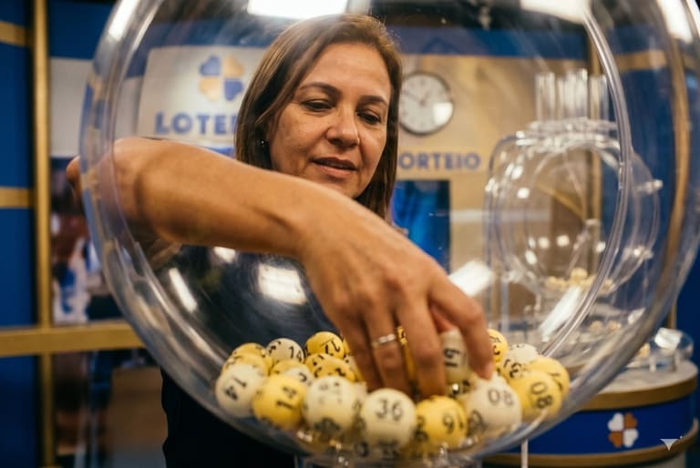 Mulher retira bola numerada de globo transparente em sorteio da Loteria do Ceará em Fortaleza, com painel azul ao fundo