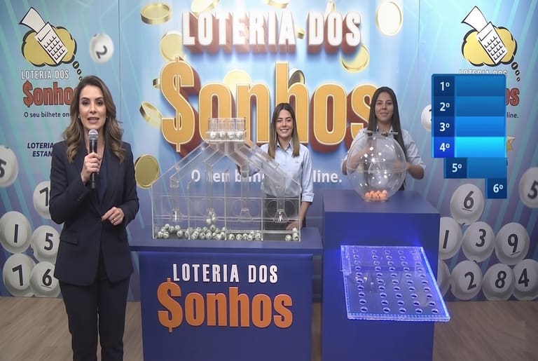Apresentadora com microfone e duas auxiliares realizam sorteio da Loteria dos Sonhos com globos e bolas