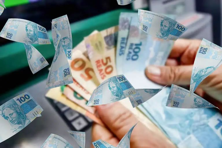 Notas de R$ 100 sobre imagem de dinheiro sendo sacado, representando o pagamento da segunda parcela do 13º salário do INSS.