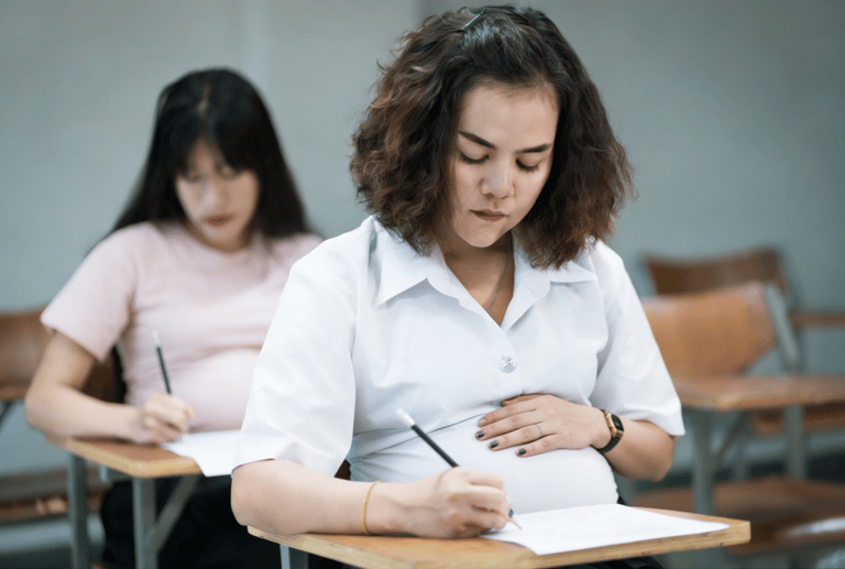 Mulheres grávidas realizando prova em sala de aula escolar.
