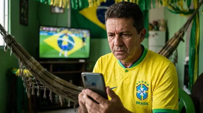 Torcedor brasileiro acompanha notícias no celular durante clima de alerta para golpes ligados à Copa de 2026.